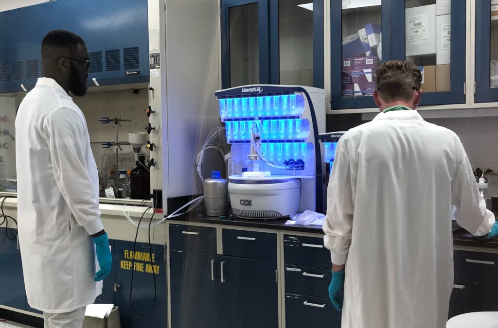 AmbioPharm and CEM scientists in front of CEM Liberty Blue microwave peptide synthesis equipment